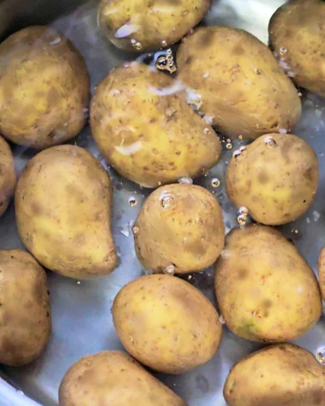 Whole potatoes in a pot of water.