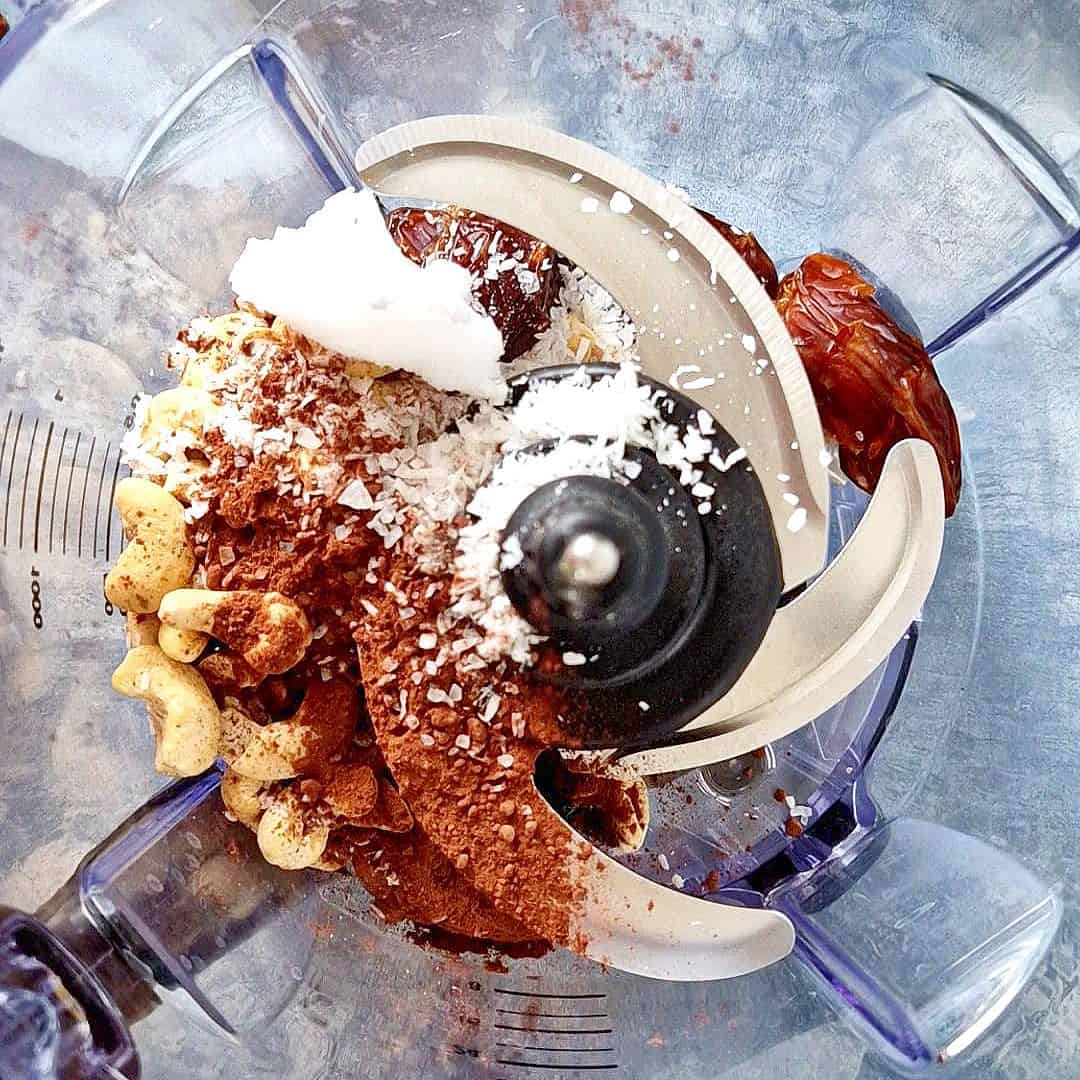 Pitted dates, cashews, coconut oil and cocoa powder in a food processor.