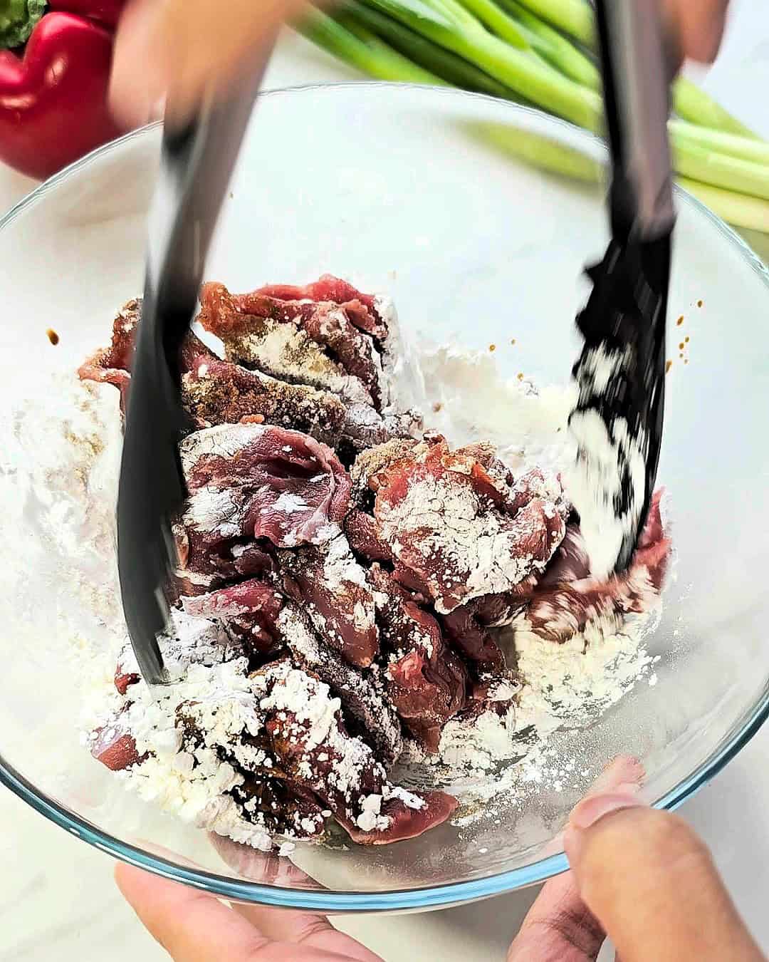 Mixing beef strips with cornstarch and seasonings.