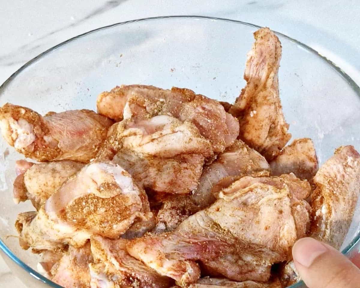 Seasoned chicken wings in a glass bowl.