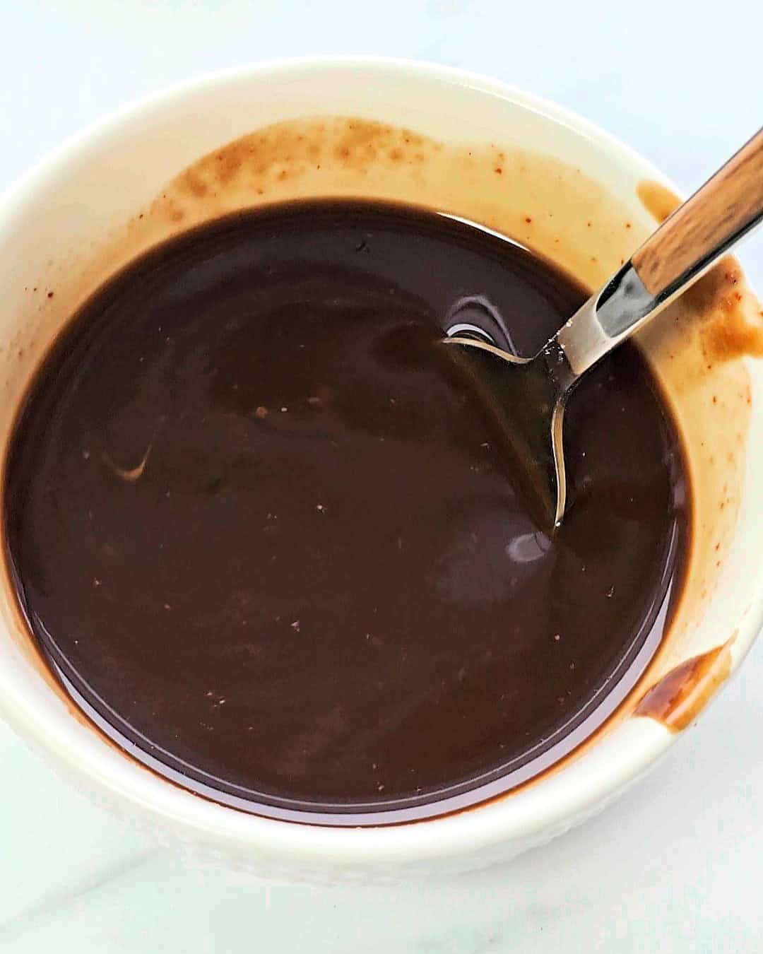 Beijing Beef sauce in a small white bowl with a spoon inside.