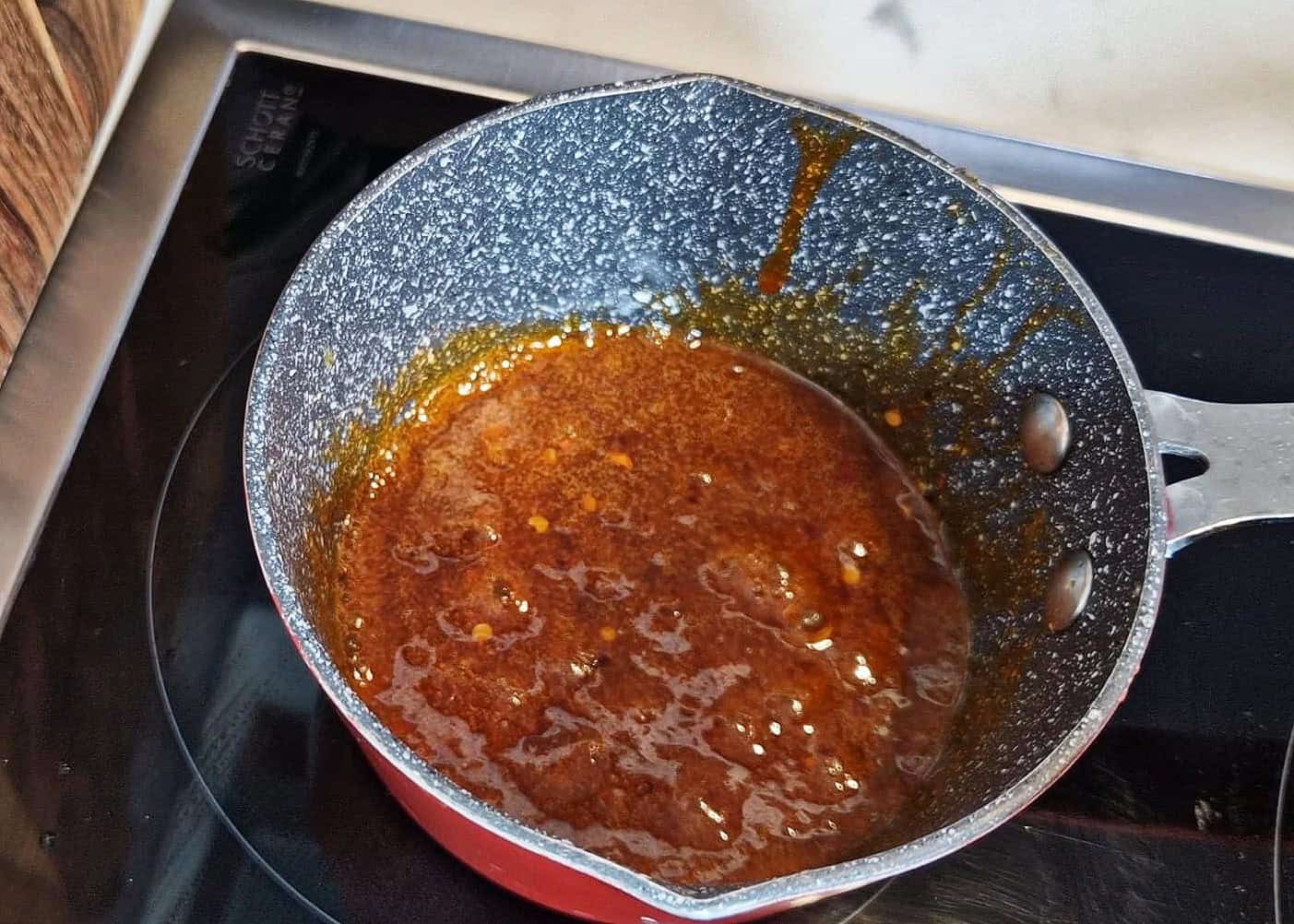 Hot honey sauce simmering in a small pot.