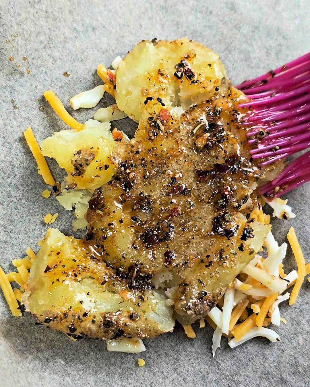 Brushing seasoned oil on a smashed potato.