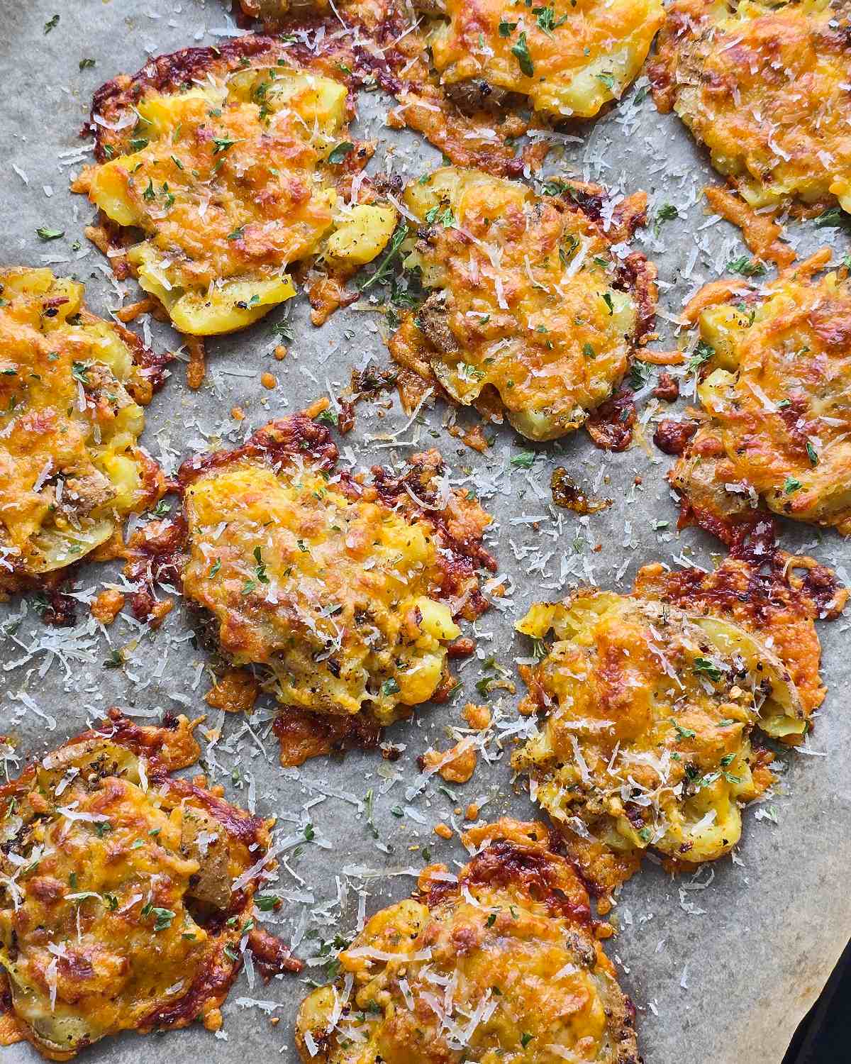 Baked cheesy smashed potatoes with grated Parmesan on top.