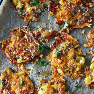 Cheesy smashed potatoes on a parchment paper.