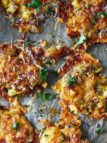 Cheesy smashed potatoes on a parchment paper.