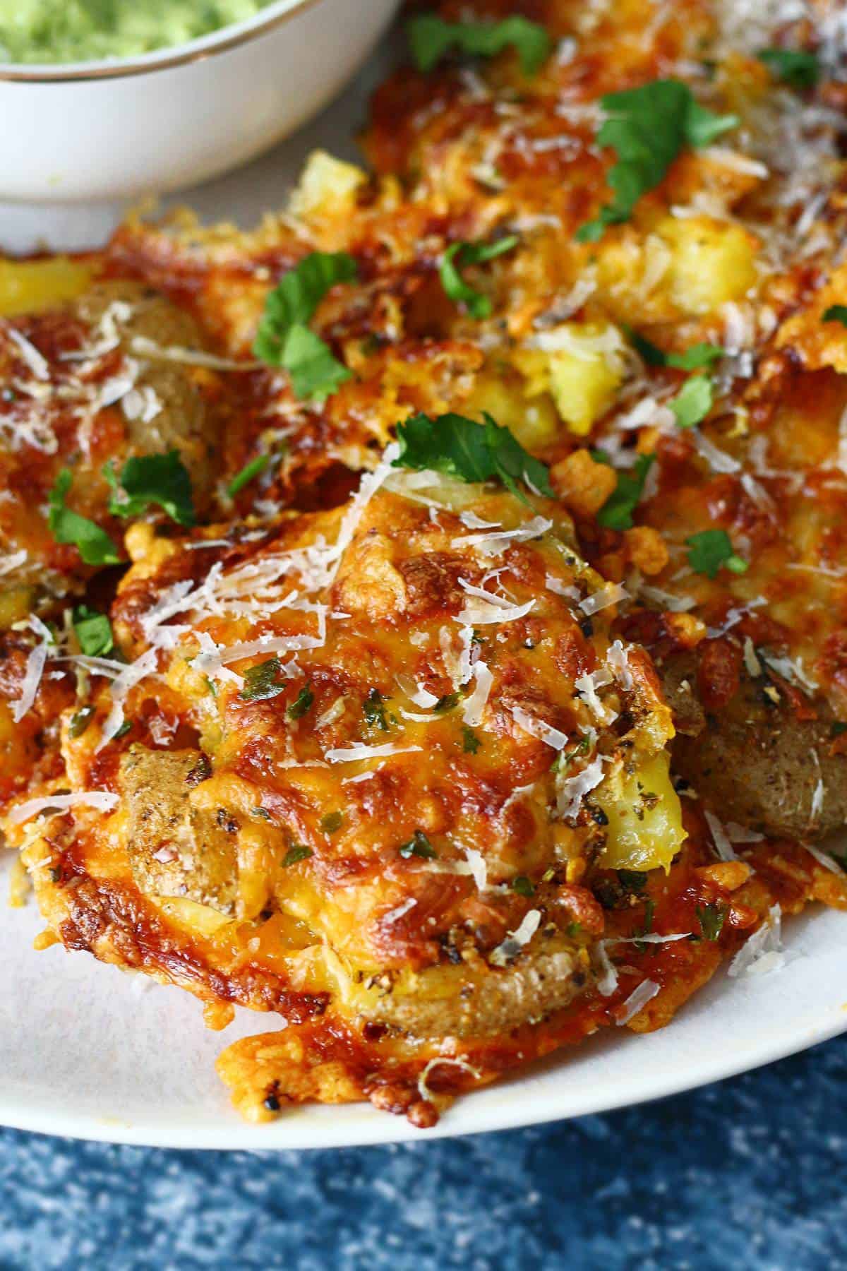 Close up of cheesy smashed potato with a sprinkling of Parmesan cheese.