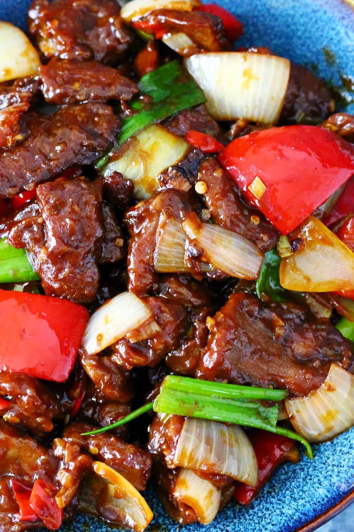 Close up of Beijing Beef with cubed red peppers and onions.