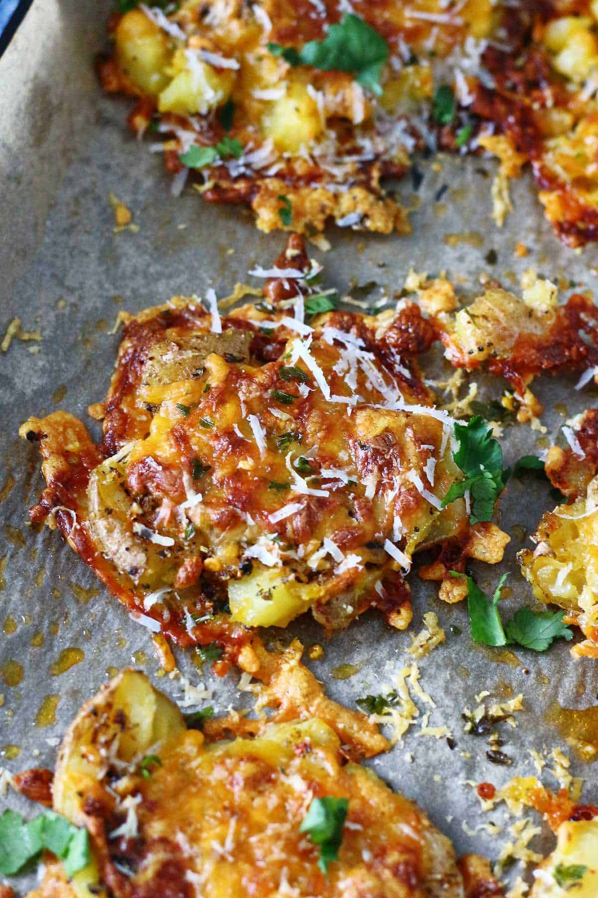 Cheesy smashed potato garnished with grated Parmesan and chopped cilantro.