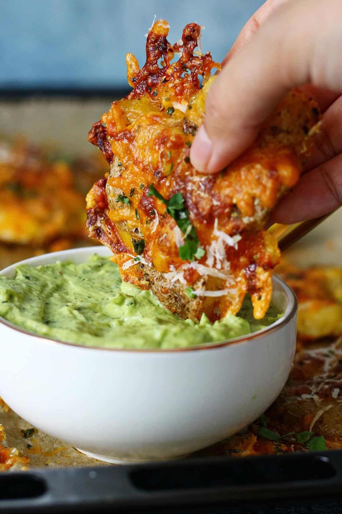 Dipping a smashed potato into a bowl of avocado crema.