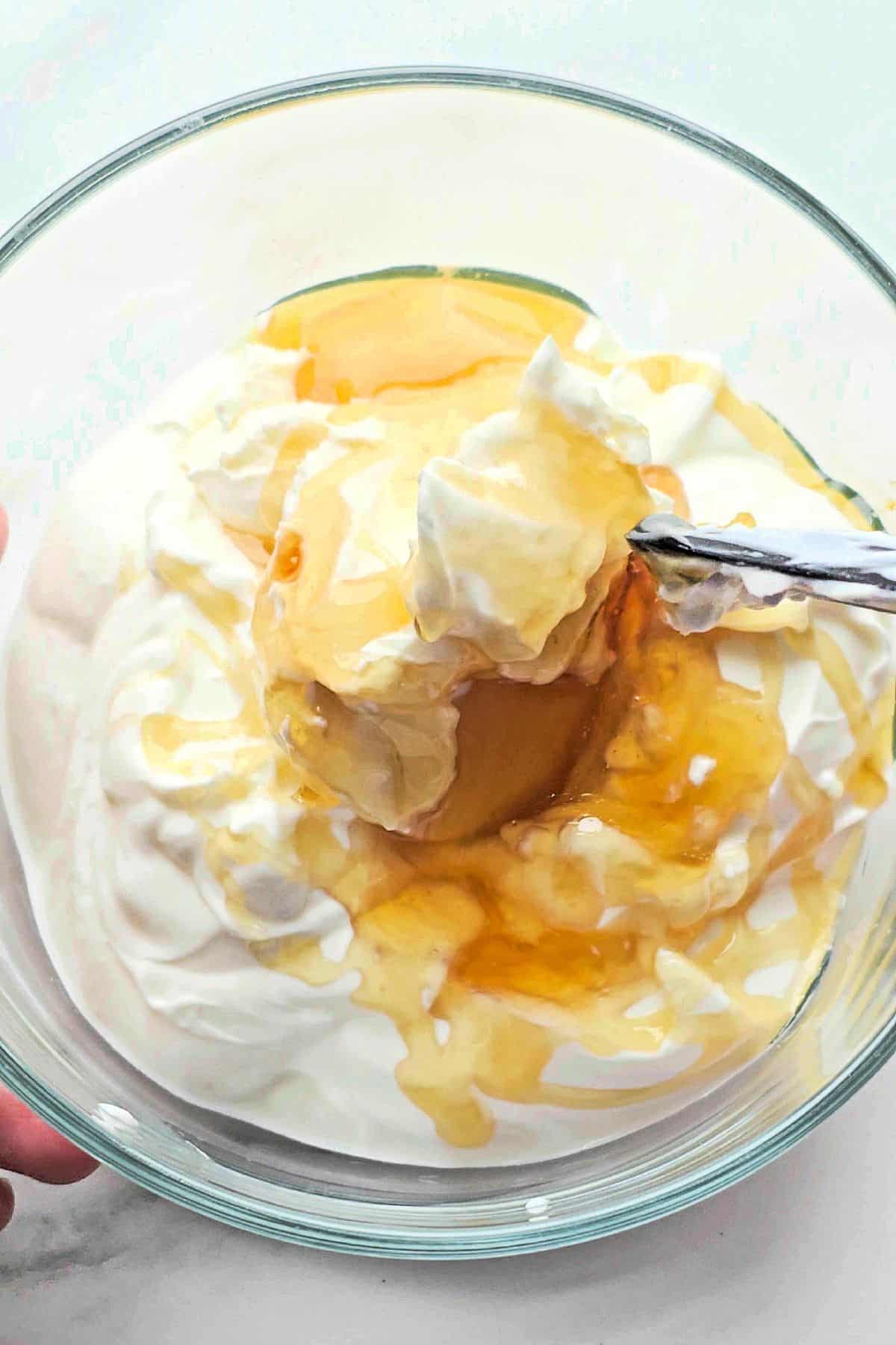 Mixing greek yogurt with honey and cream cheese in bowl.