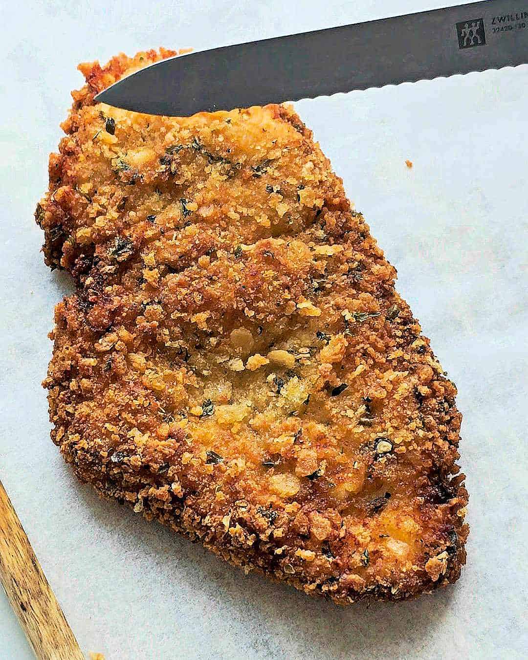 Crispy fried chicken cutlet on a white baking paper.