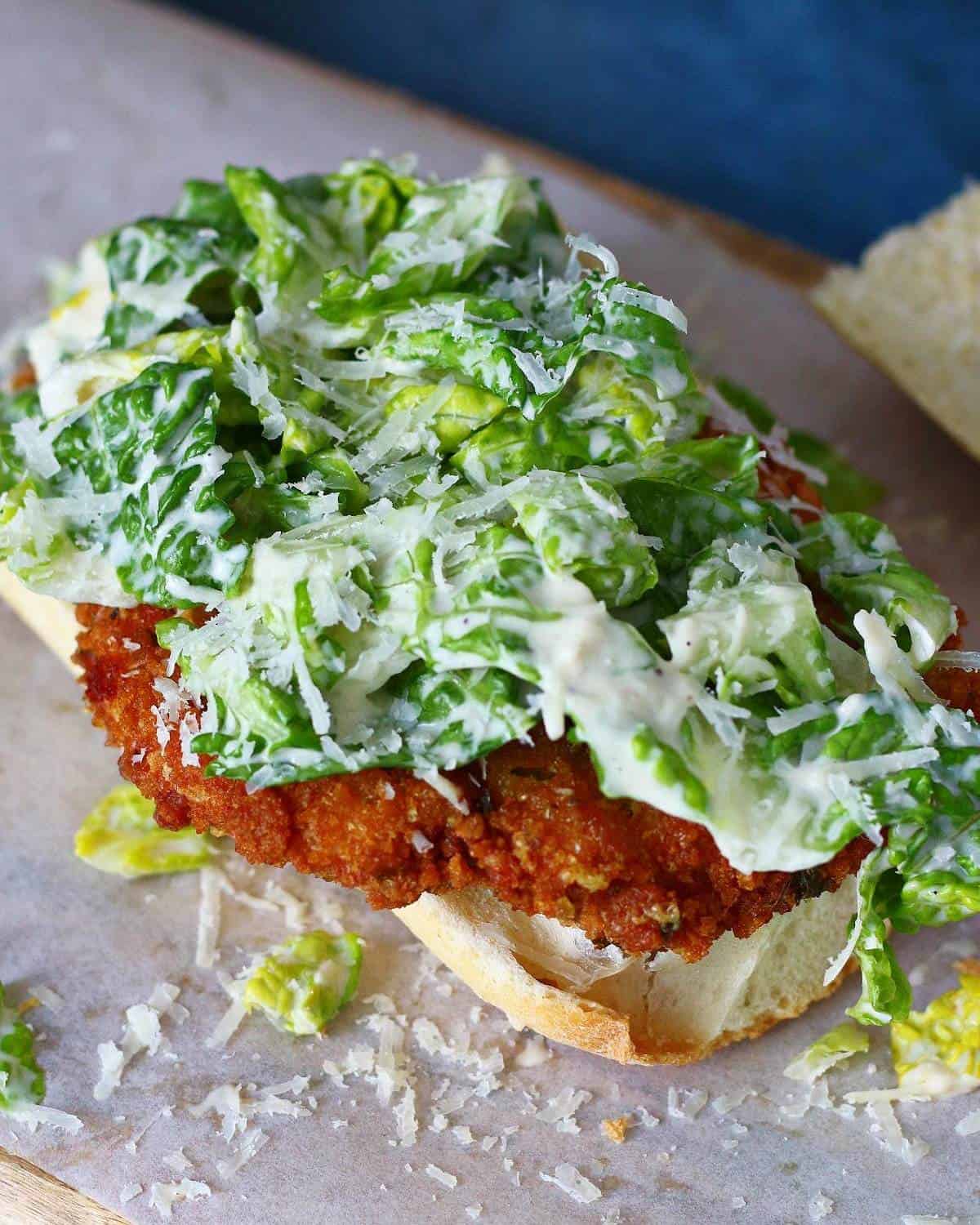 Open face chicken caesar sandwich with shredded parmesan cheese.