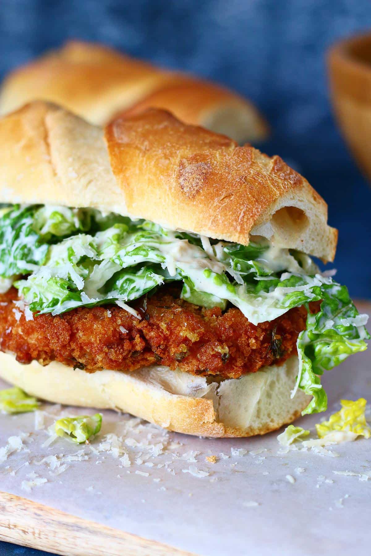 Close up of chicken Caesar sandwich with crispy chicken and creamy romaine, inside a baguette.