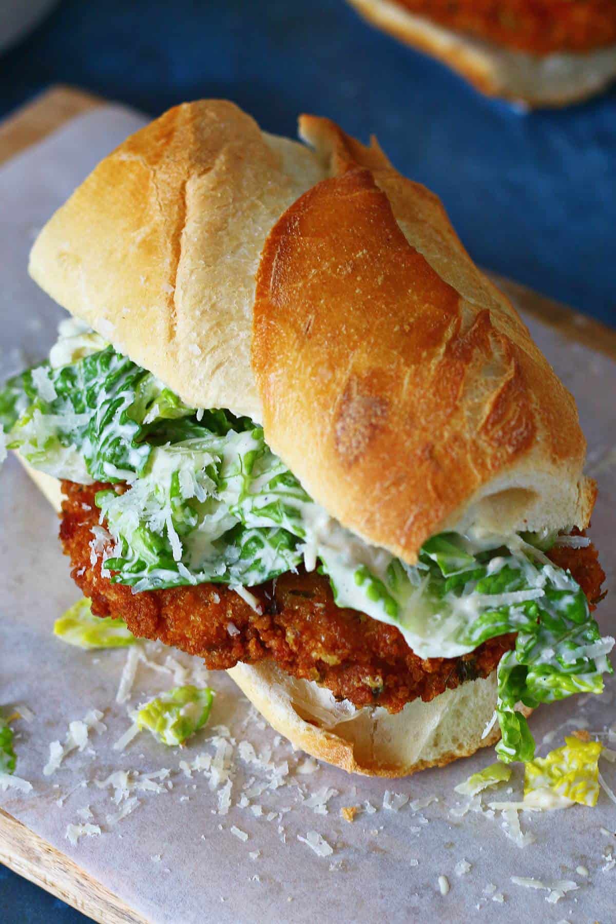 Crispy chicken baguette with grated Parmesan on a baking paper.