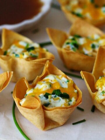 Wonton cups filled with cream cheese filling and topped with diced jalapeno.