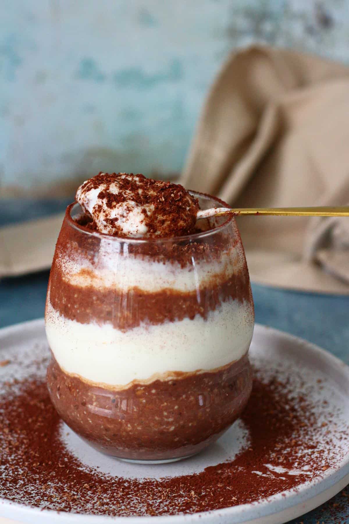 A spoonful of overnight oats on the rim of glass.