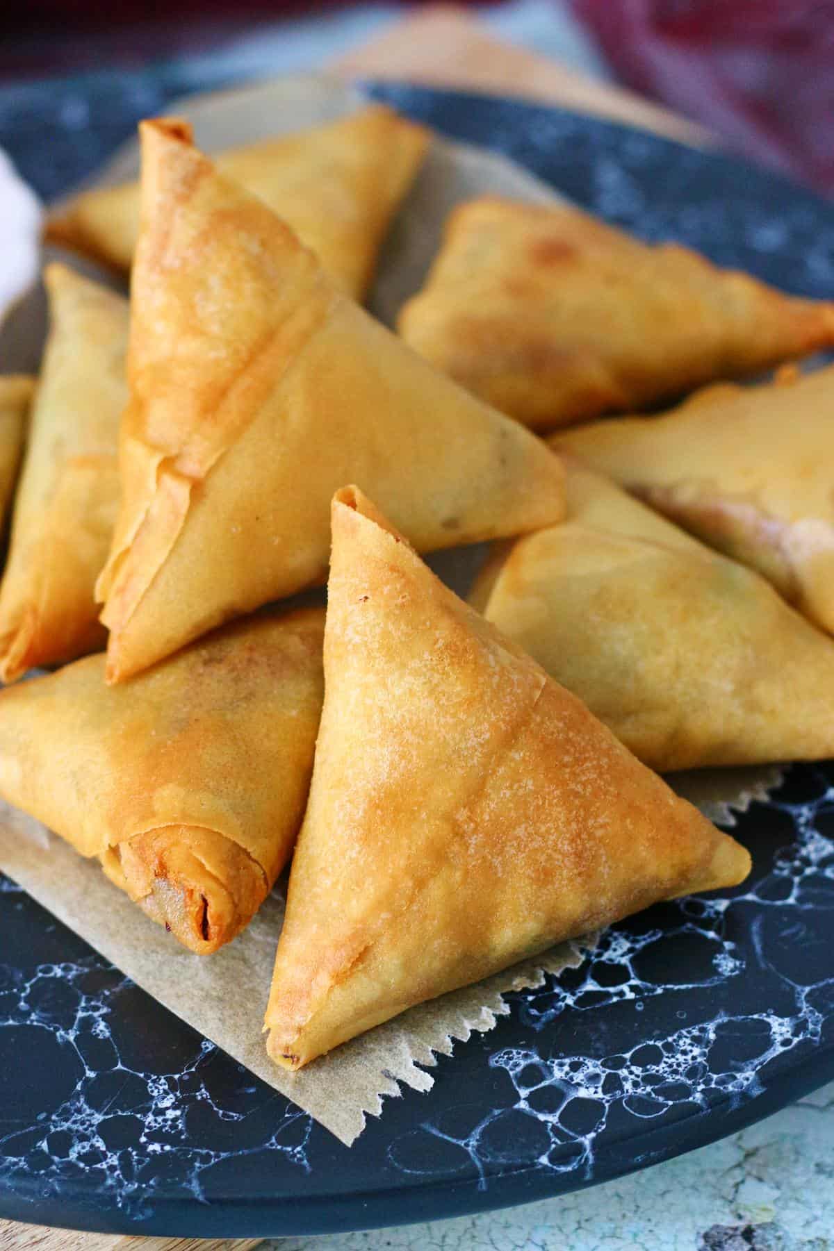 Close up of a fried beef samosa on a parchment paper.